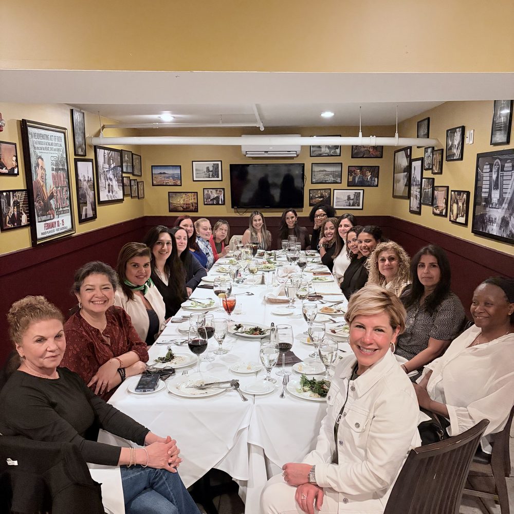 Women seated together around a long dinner table at a previous evening